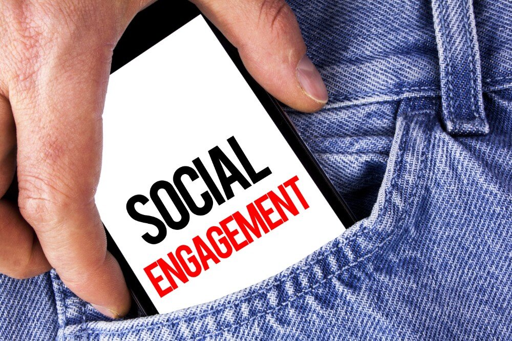 socialmedia-deel22 Hand haalt smartphone met tekst 'Social Engagement' uit spijkerbroekzak
