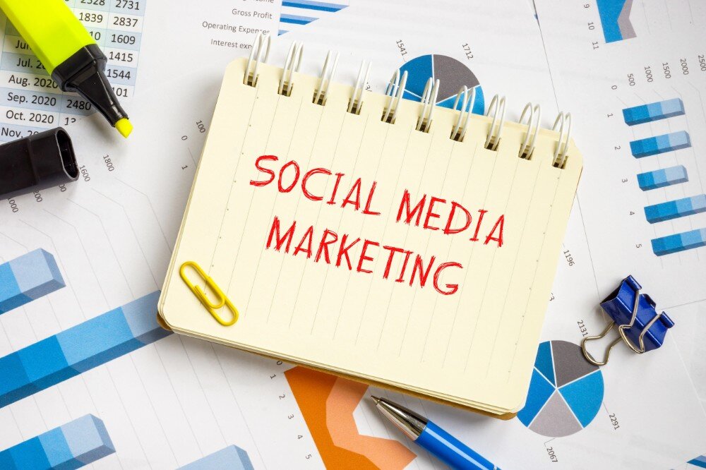 socialmedia13 Notitieboek met tekst 'Social Media Marketing', omringd door grafieken, markeerstiften en kantoorartikelen.
